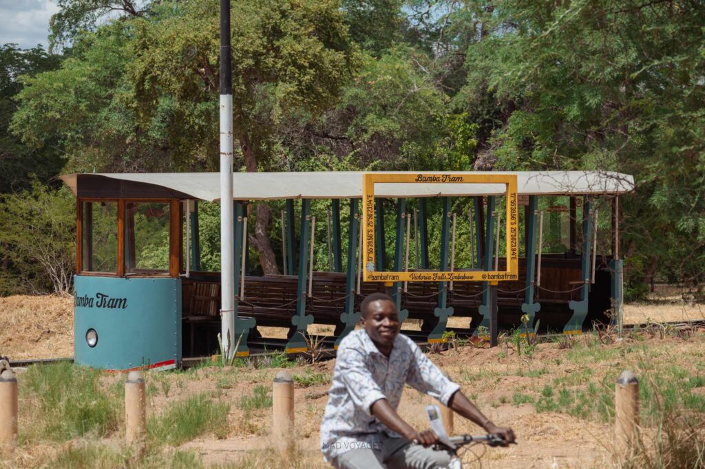 Зимбабвиец на велосипеде напротив трамвая Bamba Tram